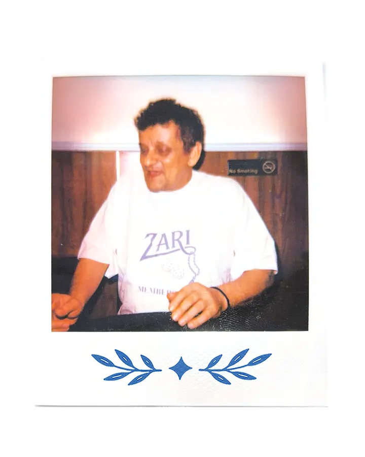 A member at the studio desk in the Zari tee, mid laugh.